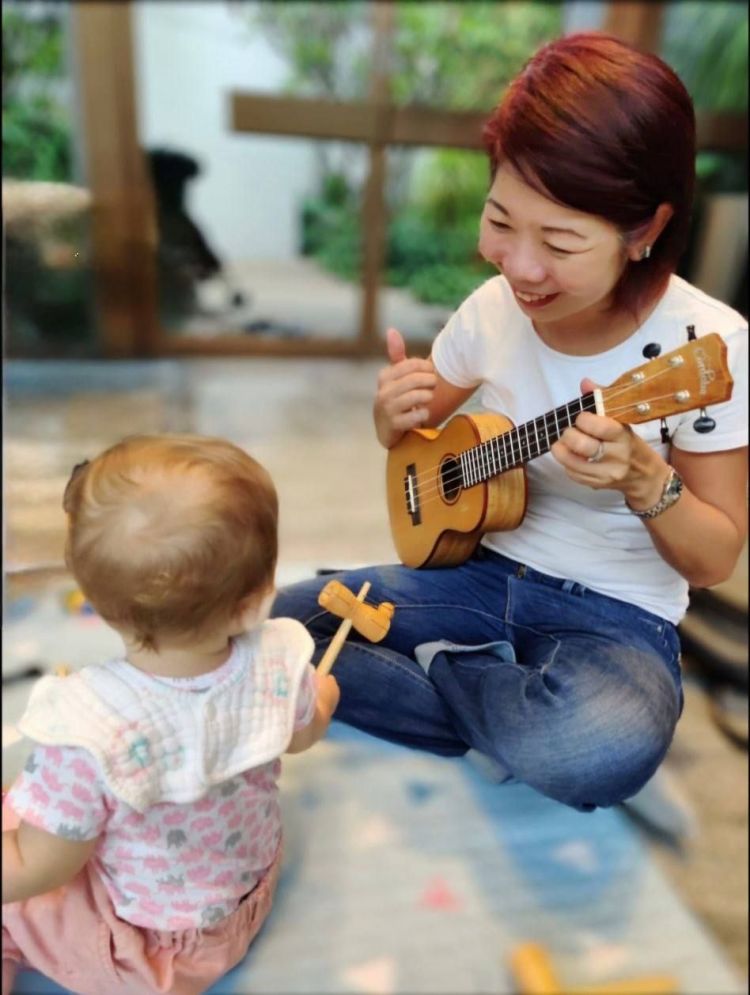 Baby music class teacher singing and playing ukulele during playgroup session